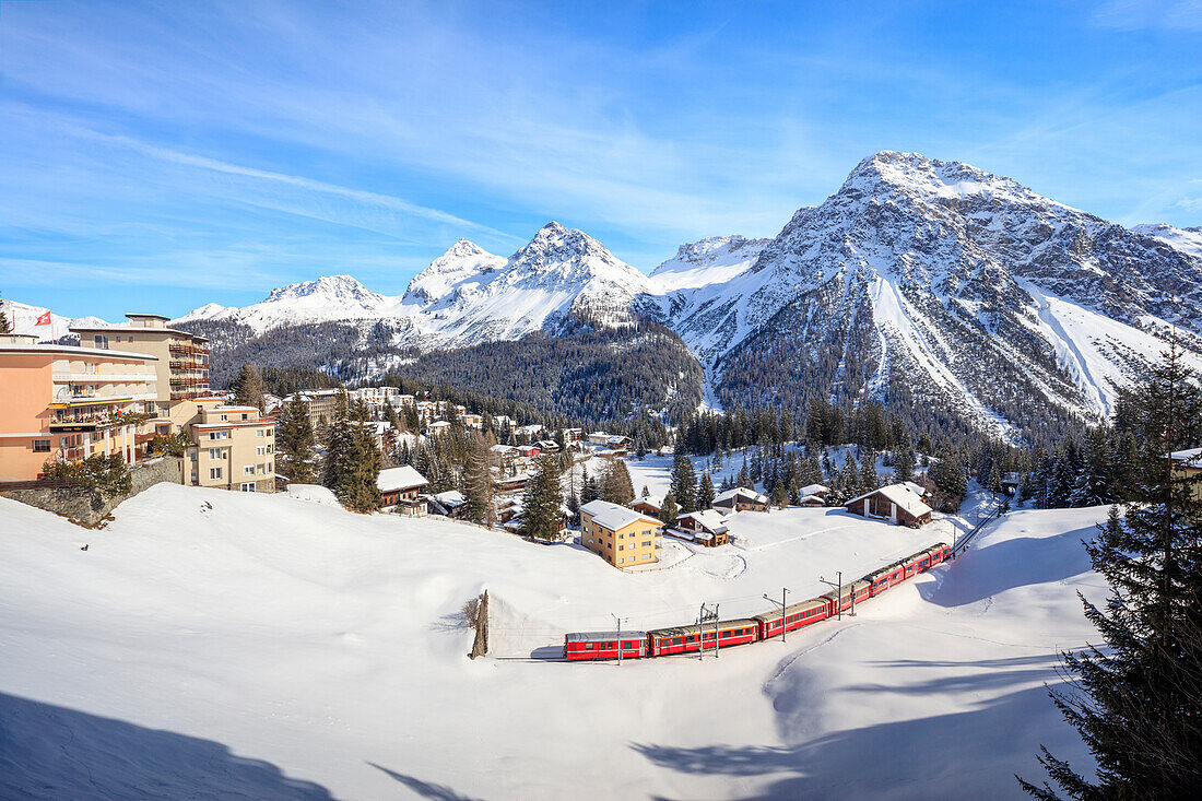 Red train of Rhaetian Railway passes in the snowy landscape of Arosa, district of Plessur, Canton of Graubunden, Swiss Alps, Switzerland, Europe