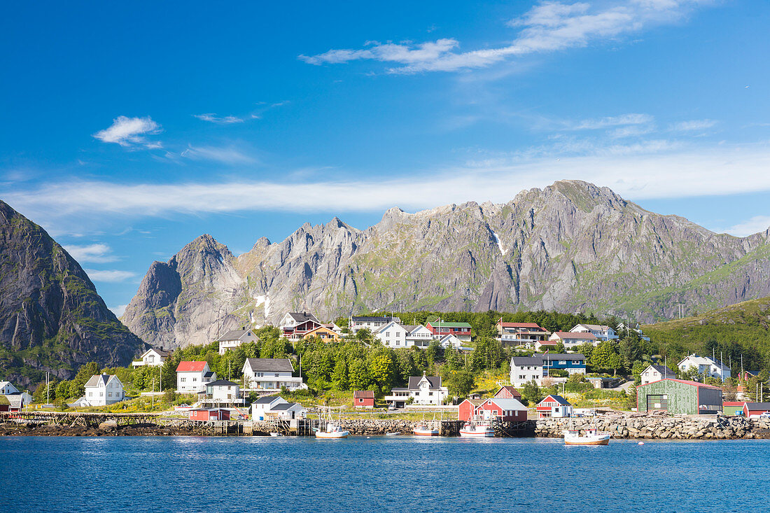 The blue sea frames the fishing village and the rocky peaks, Reine, Moskenesoya, Lofoten Islands, Norway, Scandinavia, Europe