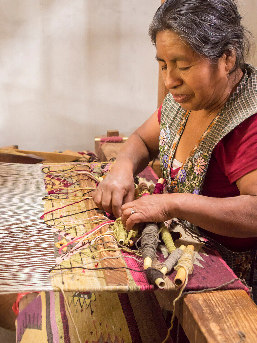 Zapotec woman weaving a rug on a floor loom in farmhouse, Teotitlan del Valle, Oaxaca, Mexico, North America