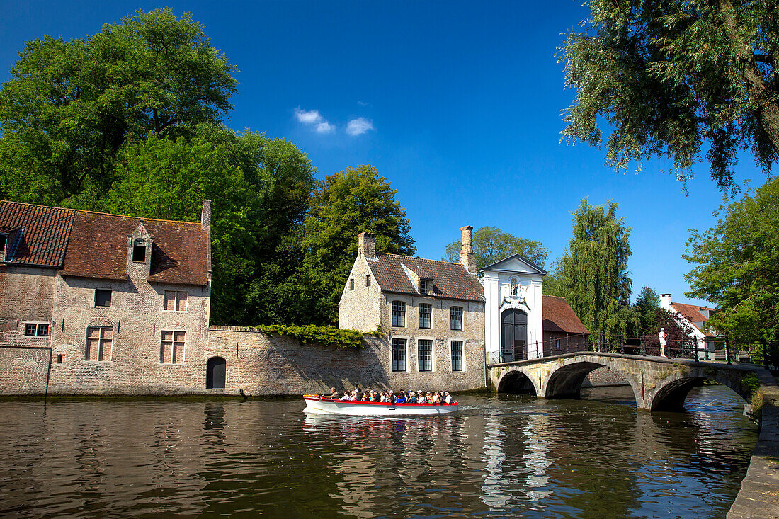 Tourist boat, at the Minnewater Lake and Begijnhof Bridge with entrance to Beguinage, Bruges, Belgium, Europe