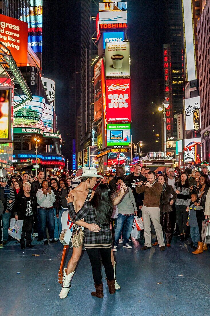 The Naked Cowboy poses for photographs with tourists in Times Square, New York, USA