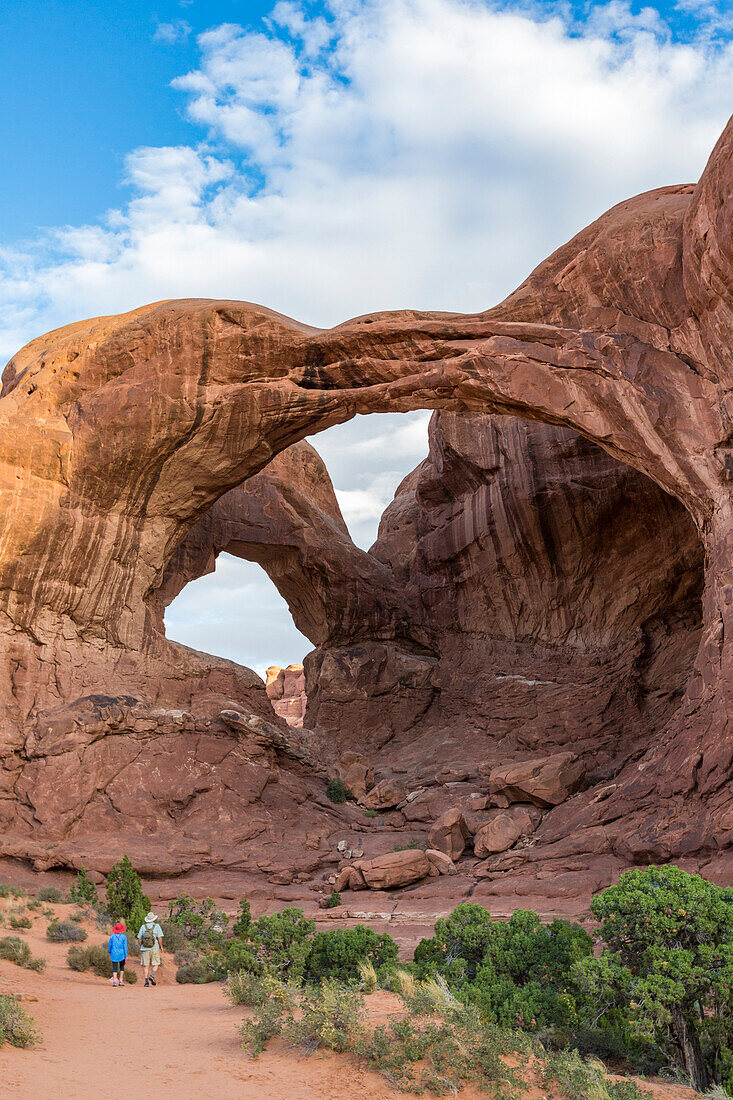 Two people in front of Double Arch, Arches National Park, Moab, Grand County, Utah, USA