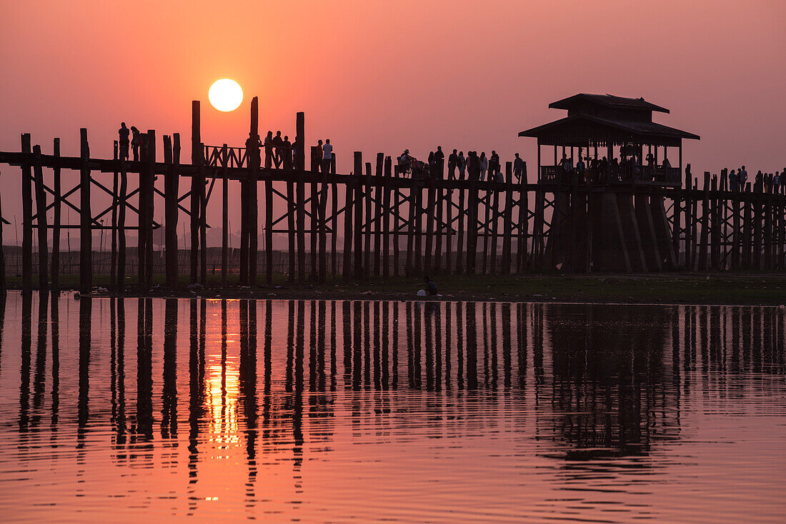 Amarapura, Mandalay region, Myanmar, Silhouetted people walking on the U Bein bridge at sunset