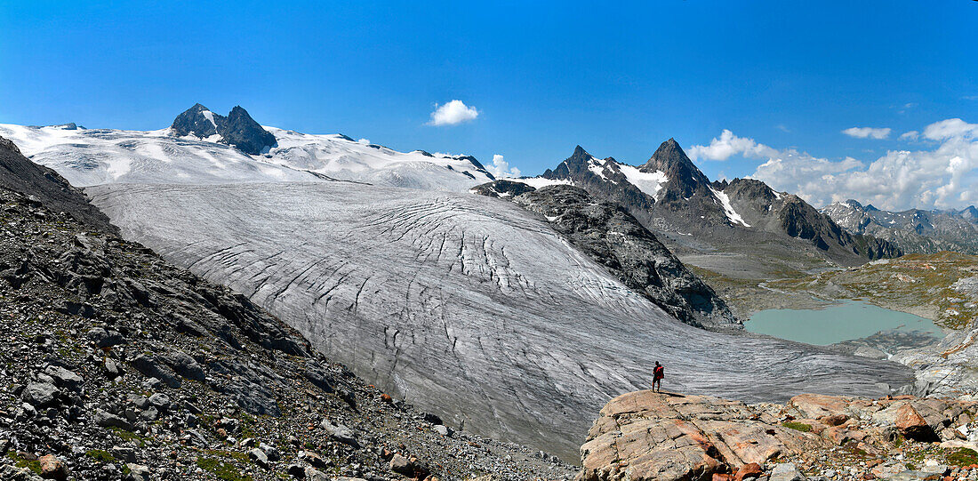 Trekker admire Rutor glacier, close to Deffeyes refuge, Grand Assaly summit on background, La Thuile valley, Aosta Valley, Italy, Europe