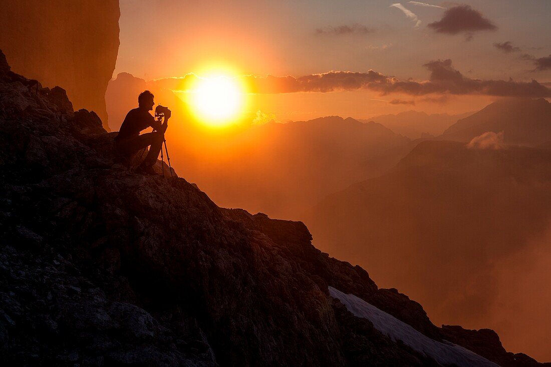 Photographer meditates in front of the sunset on the Cadini di Misurina, Dolomites, Veneto, Italy Europe
