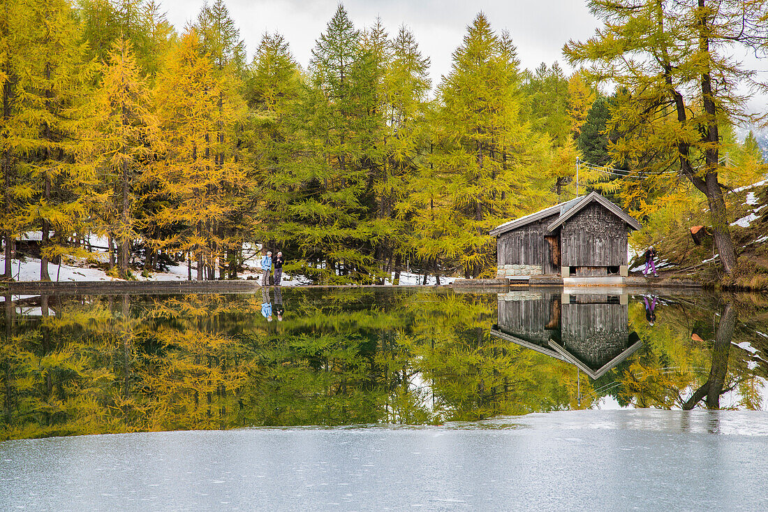 Wooden cabin and colorful trees reflected in Lai da Palpuogna Albula Pass Berg++n Canton of Graub++nden Engadine Switzerland Europe