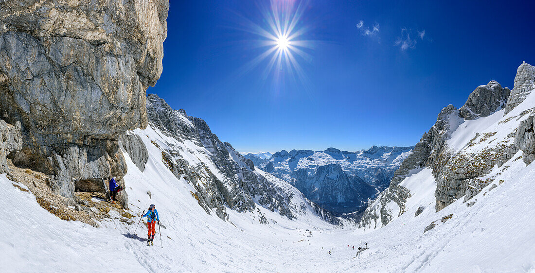 Panorama with woman backcountry skiing ascending towards Forca de la Val, Kanin group in background, Forca de la Val, Julian Alps, Friaul, Italy