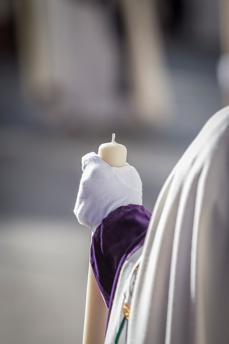 Detail penitent white holding a candle during Holy Week, Spain.