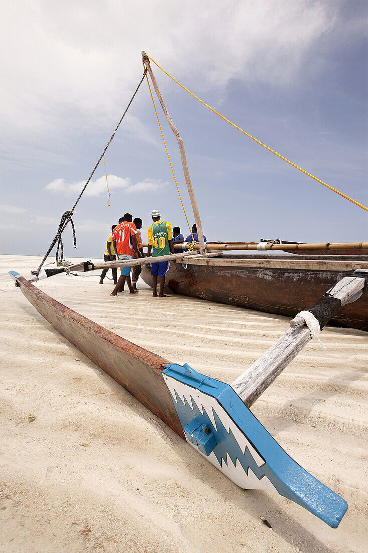 Fishermen trying to place the boat on wood blocks at the low sea level, Jambiani, Zanzibar Island, Zanzibar Archipelago,Tanzania, East Africa.