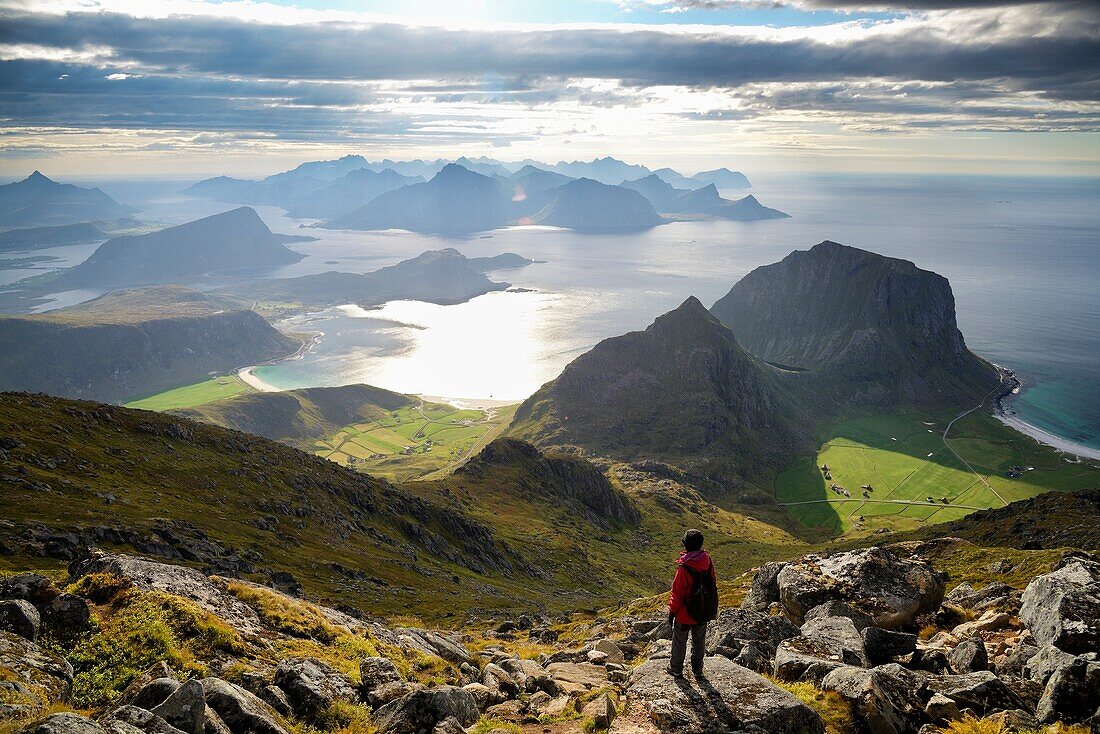 Norway, Nordland, Lofoten islands, Vestvagoy island, woman hiker at the summit of Himmeltinden (962m), view of Haukland, Vik and Utakleiv beaches below, Model Released.