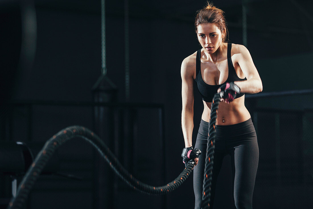 Young woman exercising with rope at gym