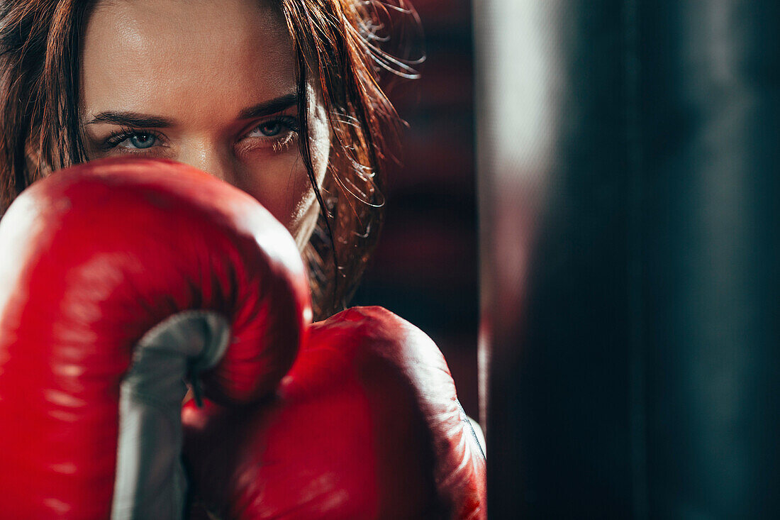 Close-up female boxer wearing punching gloves at gym