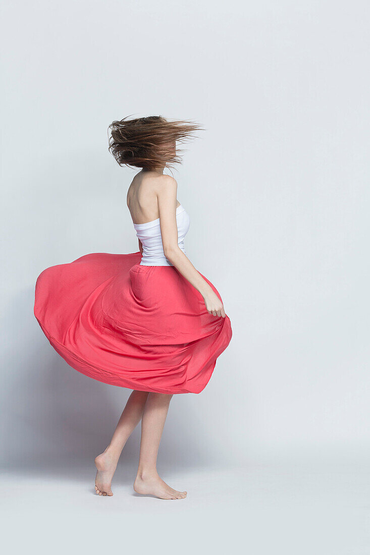 Young woman spinning against white background