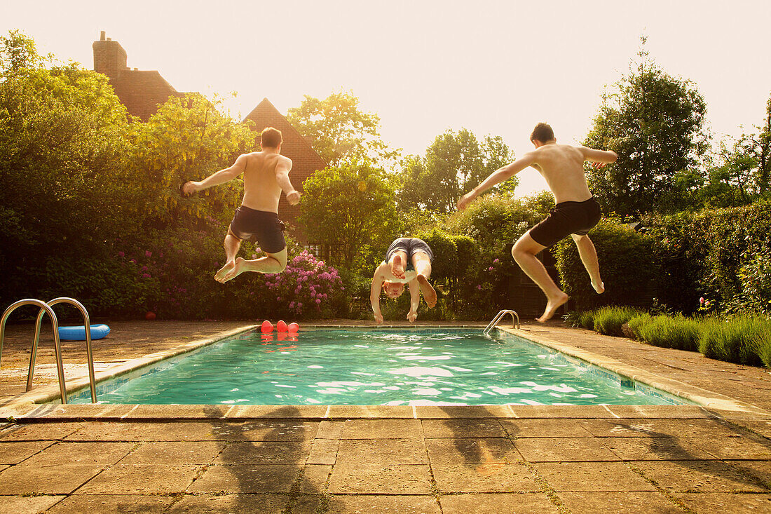 Rear view of men jumping in swimming pool during summer
