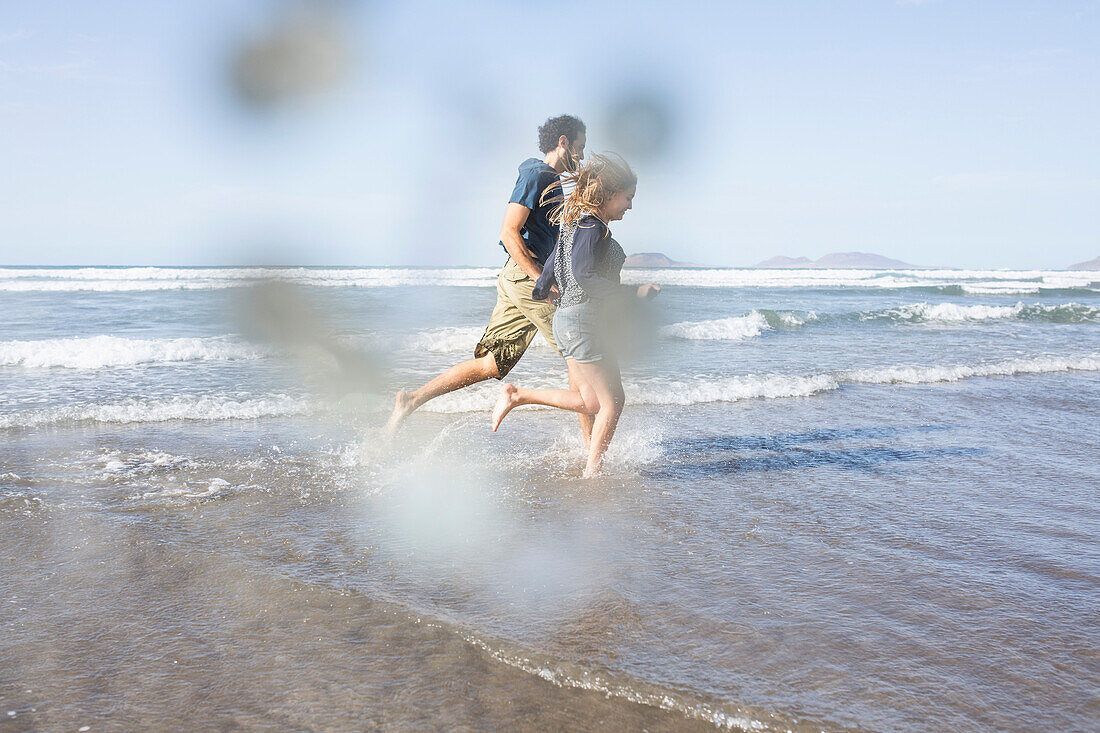 Side view of happy couple running towards sea