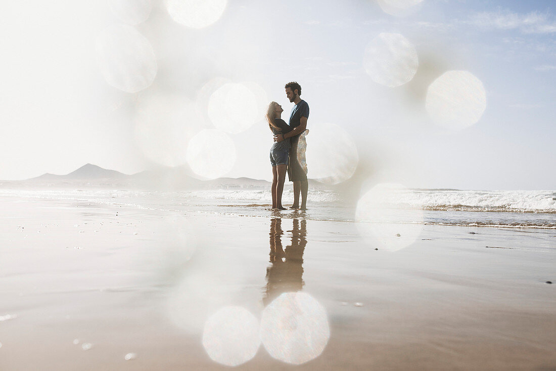 Full length of romantic couple embracing at beach