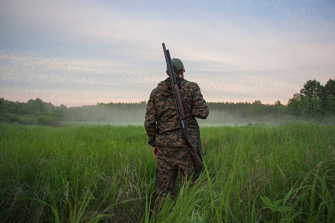Rear view of hunter standing at grassy field
