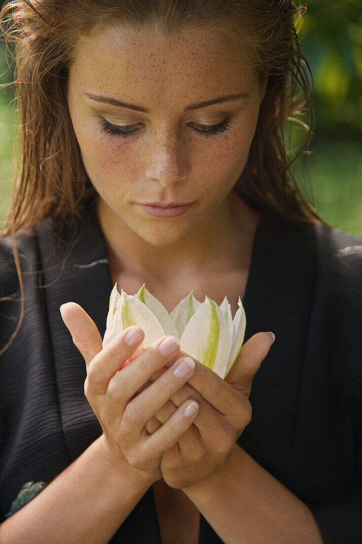 Close-up of beautiful woman holding flower at yard