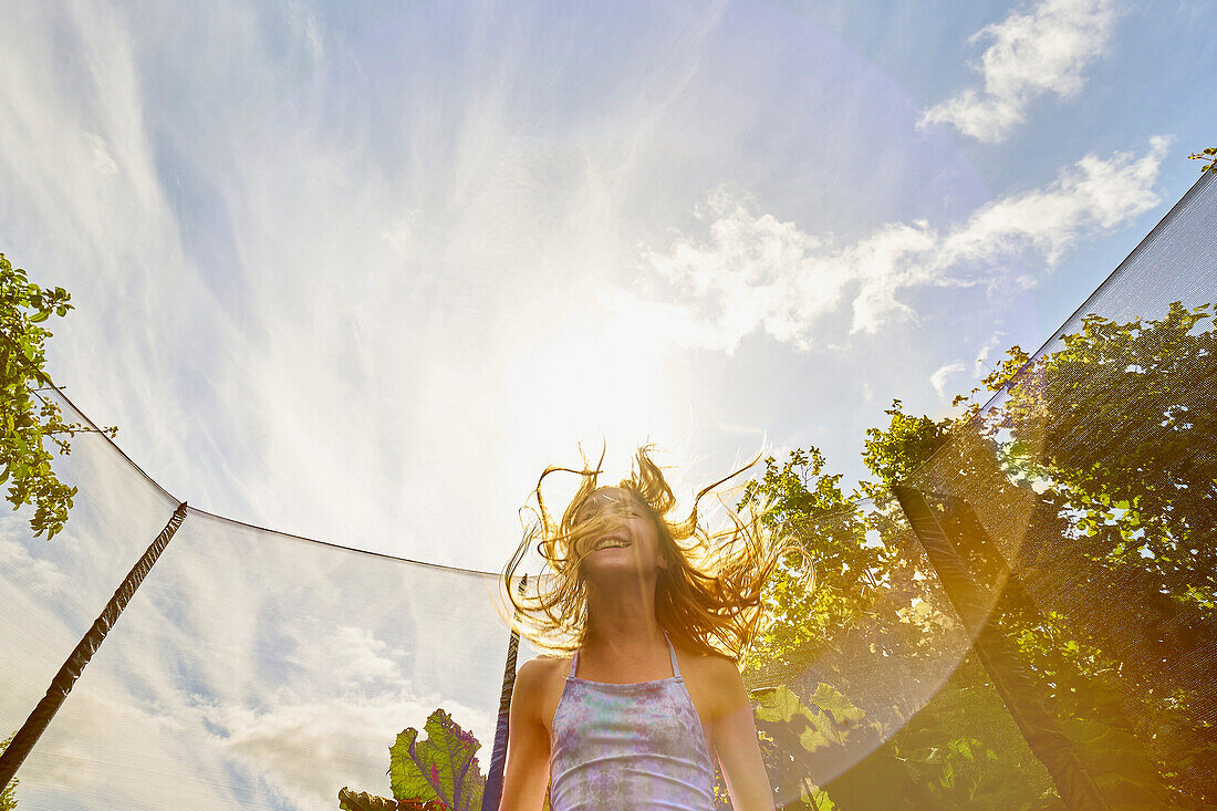 Low angle view of Caucasian girl jumping on trampoline