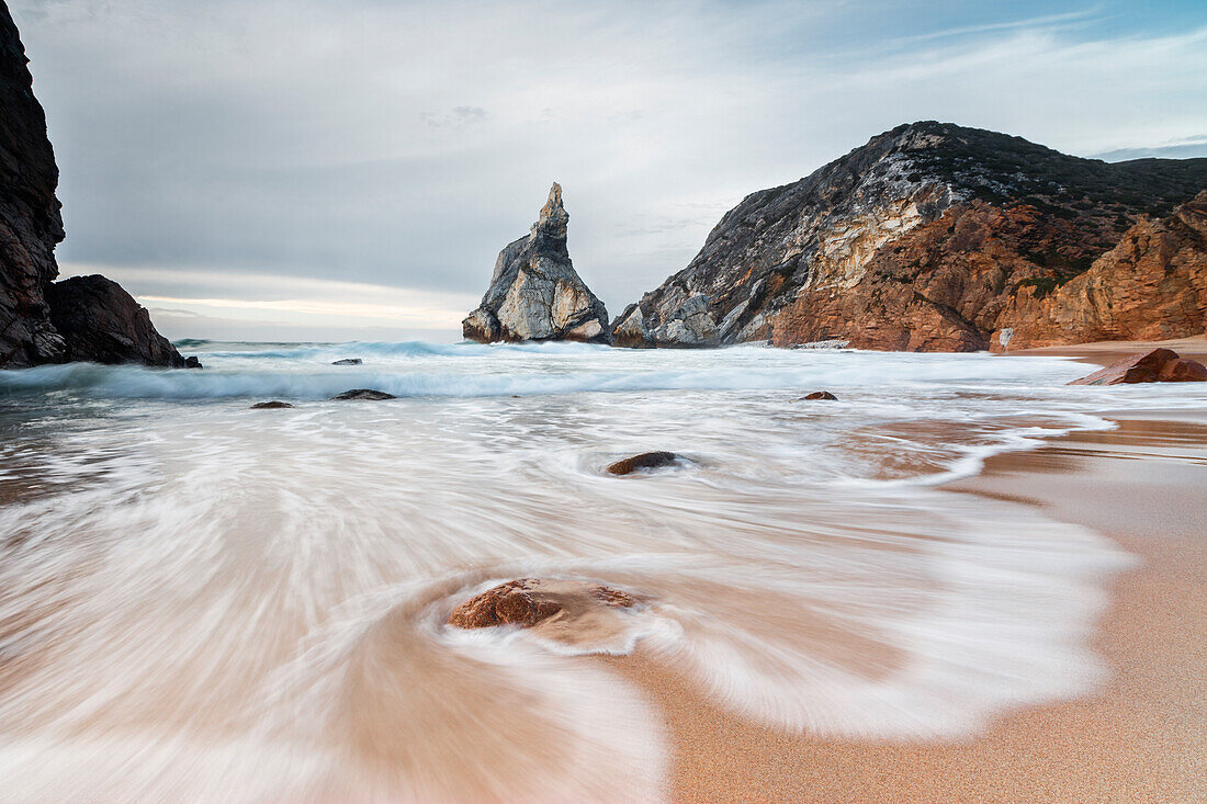 Ocean waves crashing on the sandy beach of Praia da Ursa surrounded by cliffs Cabo da Roca Colares Sintra Portugal Europe