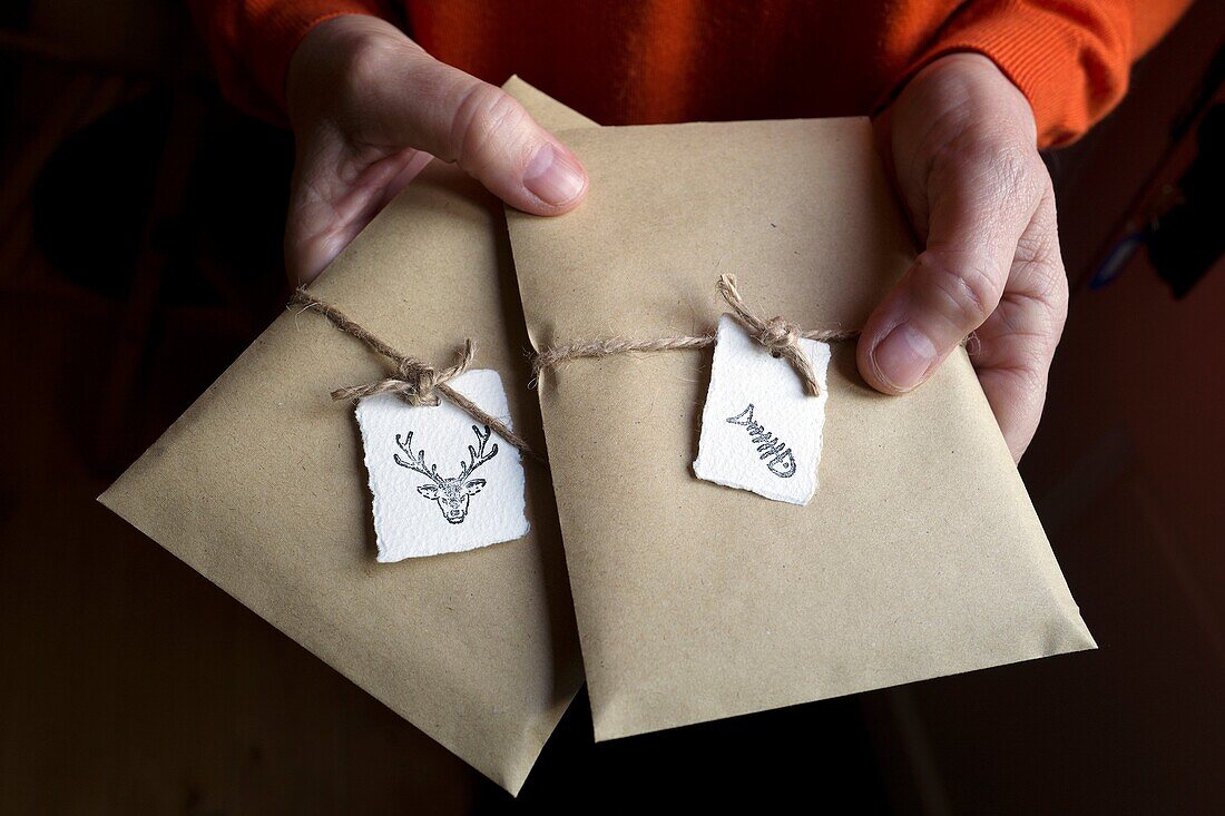 Woman's hands holding two gift packages, tied with a string and labelled with animal images
