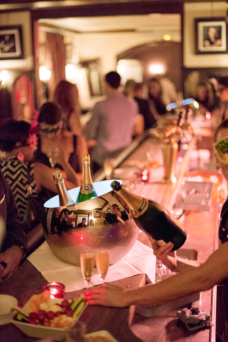 Bartender serving champagne at the bar in a party.