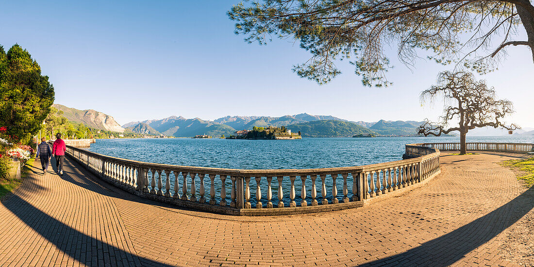 Stresa, Lake Maggiore, Verbano-Cusio-Ossola, Piedmont, Italy, Couple walking on the lake front with Borromean islands in the background