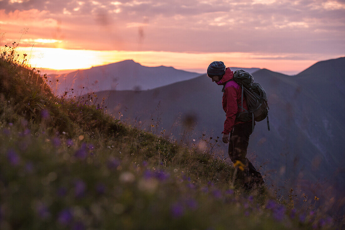 Young woman hiking up to the Muttlerkopf in the Alps at sunset
