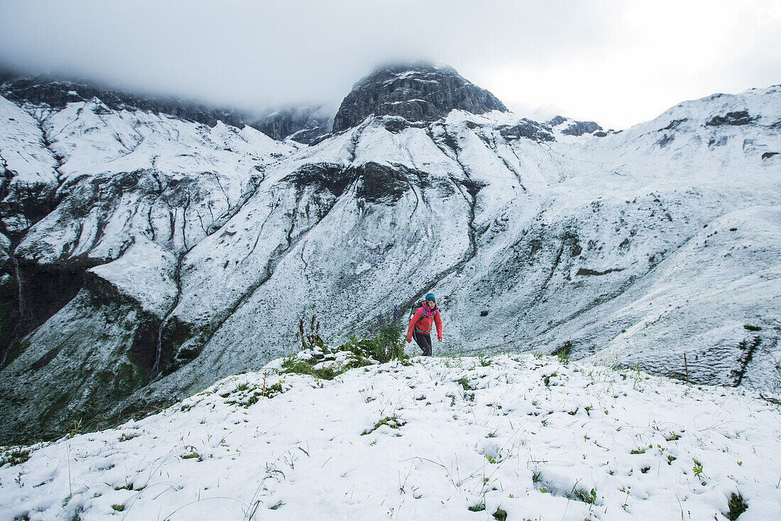 Junge Frau wandert durch den letzten Schnee auf den Muttlerkopf in den Alpen
