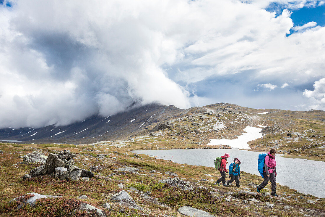 A woman and two girls are hiking on the Kungsleden trek, in the wildernes. From Kebnekaise Fjällstation to Singistugorna. Lapland, Sweden.