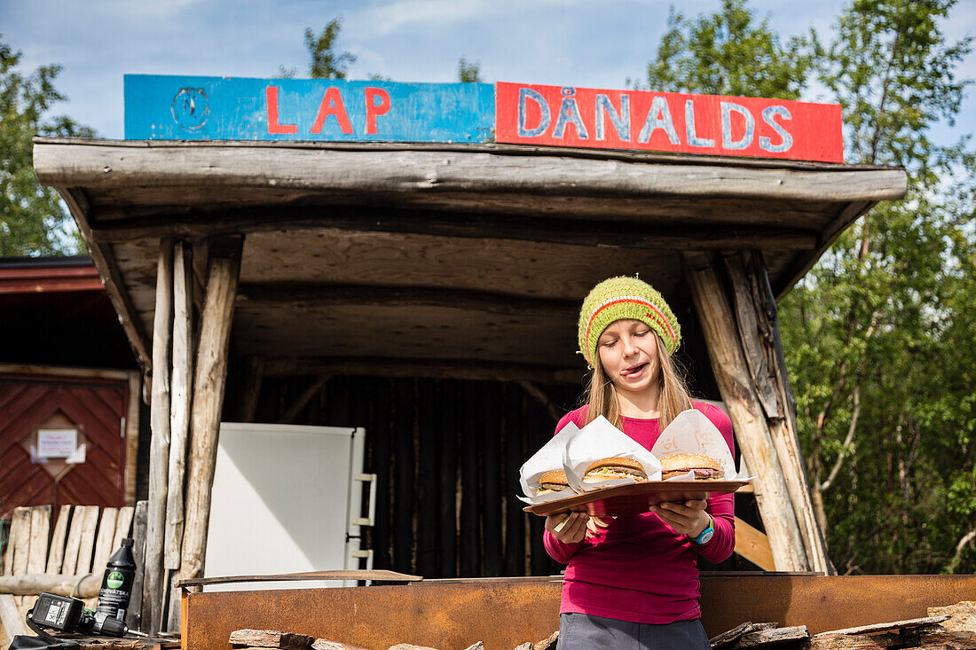 Ein Mädchen mit den Rentierhamburgern von Lap Danalds, am Ladtjojaure, Lappland, Schweden.