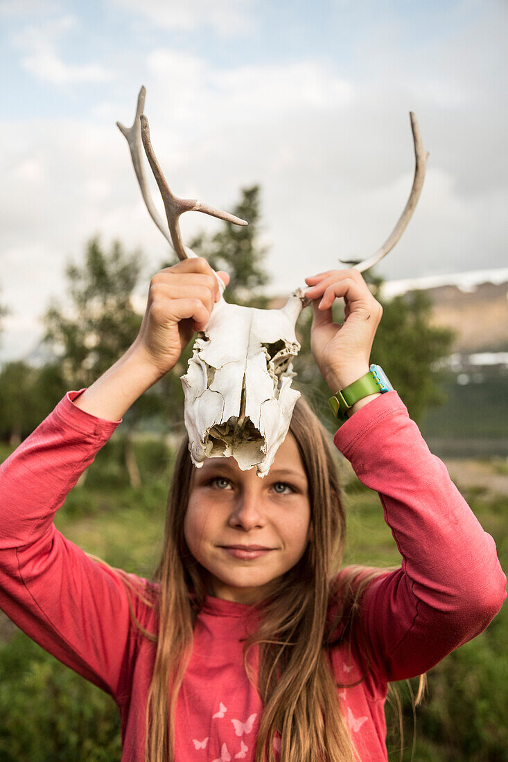 Ein Mädchen zeigt einen Schädel eines Rentiers. Kungsleden Trekking, Laponia, Lappland, Schweden.
