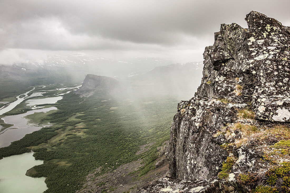 Regen und Wolken über dem Sarek Nationalpark. Tiefblick vom Gipfel des Skierffe auf das Rapadalen/Laidaure Delta, Sarek Nationalpark, Laponia, Lappland, Schweden. Trekking auf dem Kungsleden.