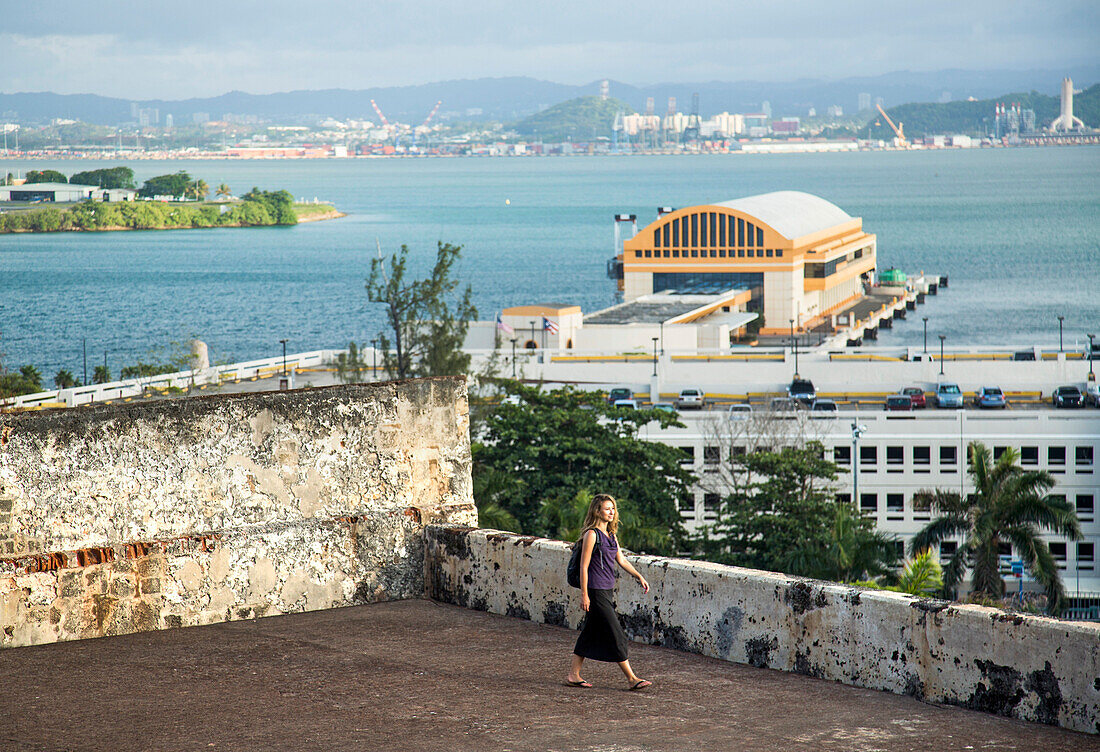 Woman Exploring A Fort Overlooking The Water Off The Coast Of San Juan, Puerto Rico