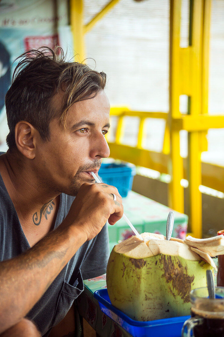 Man Drinking Coconut Juice Directly From The Coconut