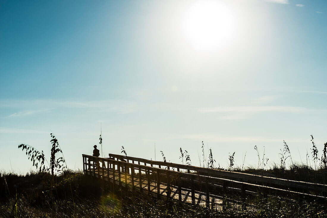 Mann auf einem Steg am Strand in einem Nationalpark im Gegenlicht, Boca Grande, Florida, USA
