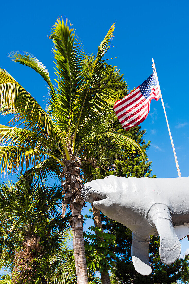 Typisches Florida mit Manateefigur, Amerikaflagge und Palmen, Fort Myers Beach, Florida, USA