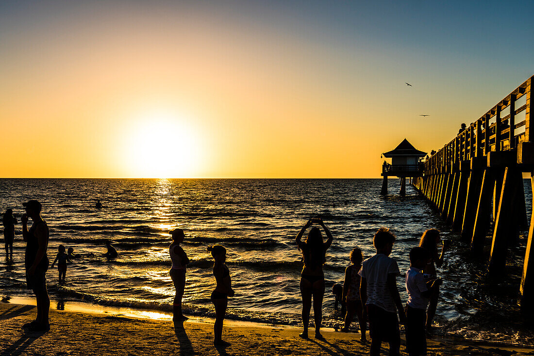 Sonnenuntergang am beliebten öffentlichen Strand am Naples Pier am Golf von Mexiko, Naples, Florida, USA