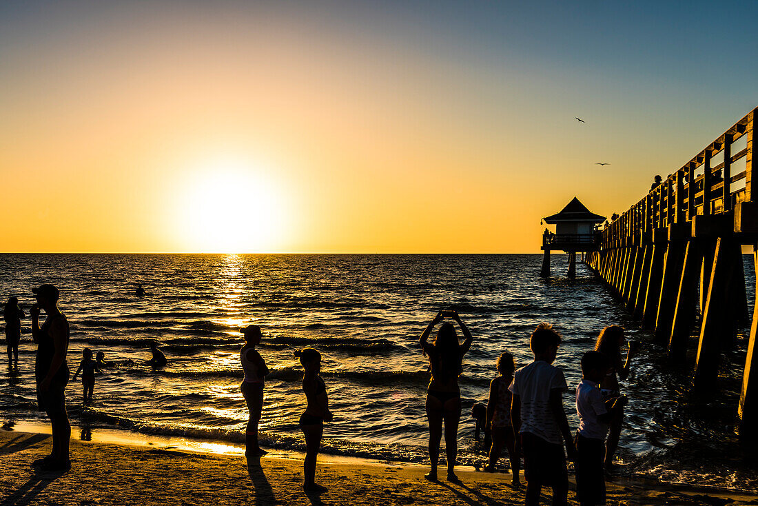 Sunset at the popular public beach at Naples pier at the Gulf of Mexico, Naples, Florida, USA