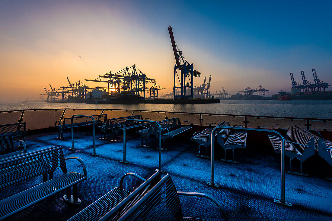 Sonnenaufgang an einem Wintertag im Hamburger Hafen am Containerterminal Burchardkai von der Elbfähre aus gesehen, Hamburg, Deutschland