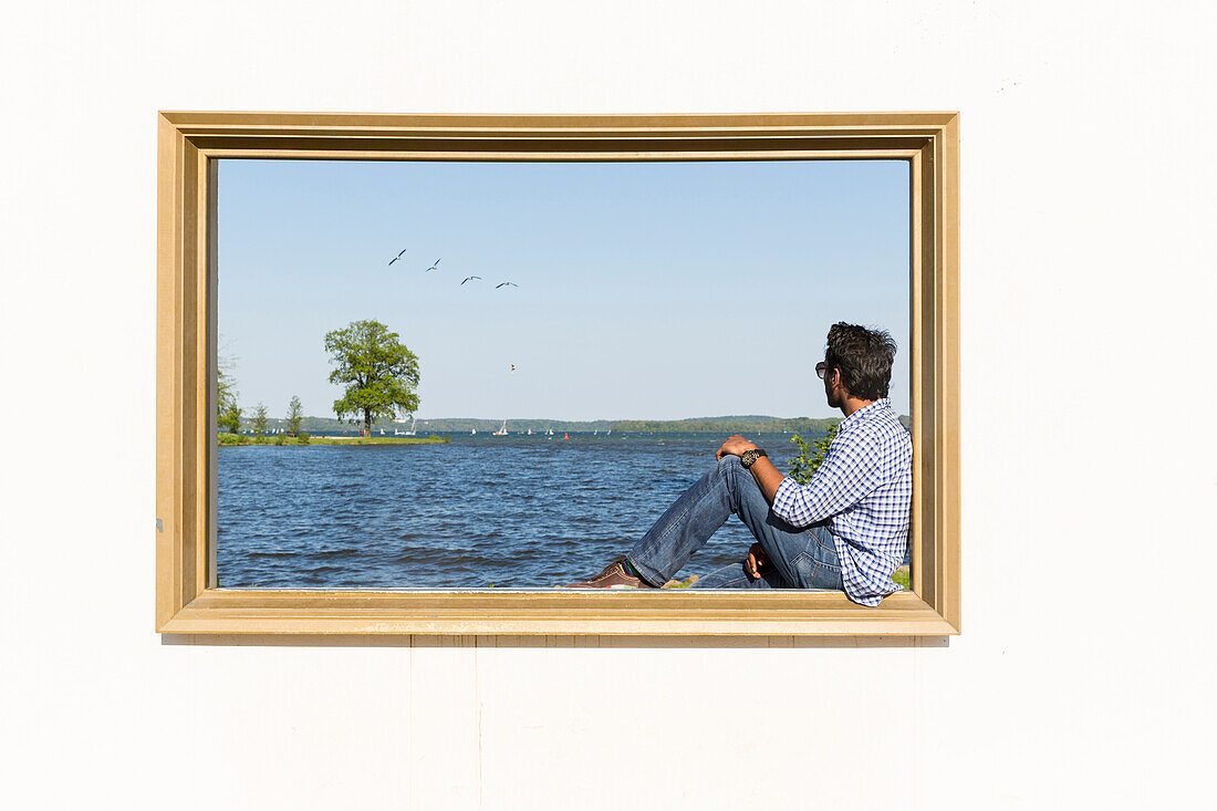 Schwerin castle, castle garden, man sitting in an over-sized photo frame for people and nature, art, provincial capital, Mecklenburg lakes, Mecklenburg-West Pomerania, Germany, Europe