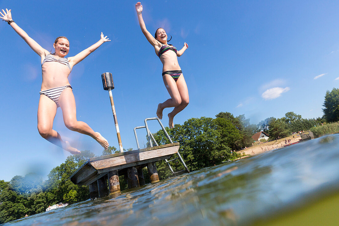 Girls jumping into the water, beach of Diemitz, lake Vilzsee, Mecklenburg lakes, Mecklenburg lake district, Diemitz, Mecklenburg-West Pomerania, Germany, Europe