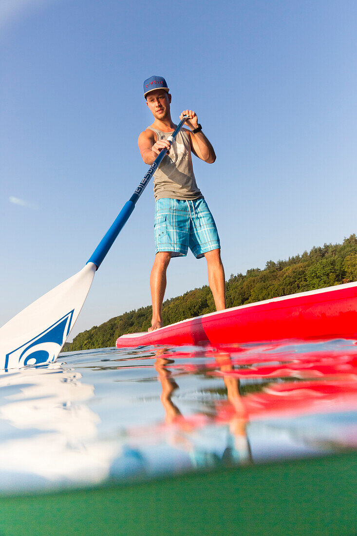 Stand up paddling auf dem See, Junge mit Paddel, rotes SUP, Wasserwandern, klarer See Schmaler Luzin, grünes Wasser, Urlaub, Sommer, Ferien, baden, schwimmen, Mecklenburgische Seenplatte, Mecklenburgische Seen, MR, Feldberg, Mecklenburg-Vorpommern, Deutsc