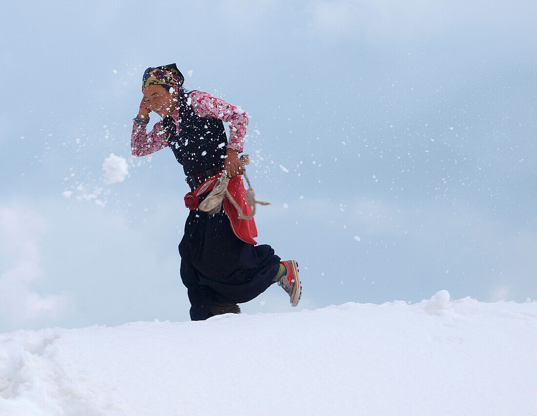 A woman porter is being hit by a snowball thrown by a fellow porter. The inhabitants of the village of Sama Goan are offering their services to expeditions on Manaslu bu carrying gear to basecamp.    The Manaslu mountain in the Nepal Himalayas is 8163 met