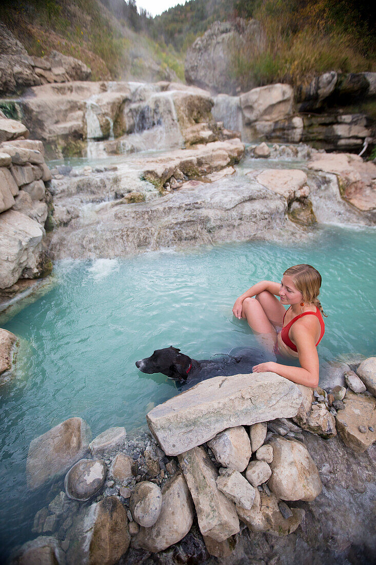 Woman With Her Dog Sitting In Water At Diamond Fork Hot Springs, Utah, Usa