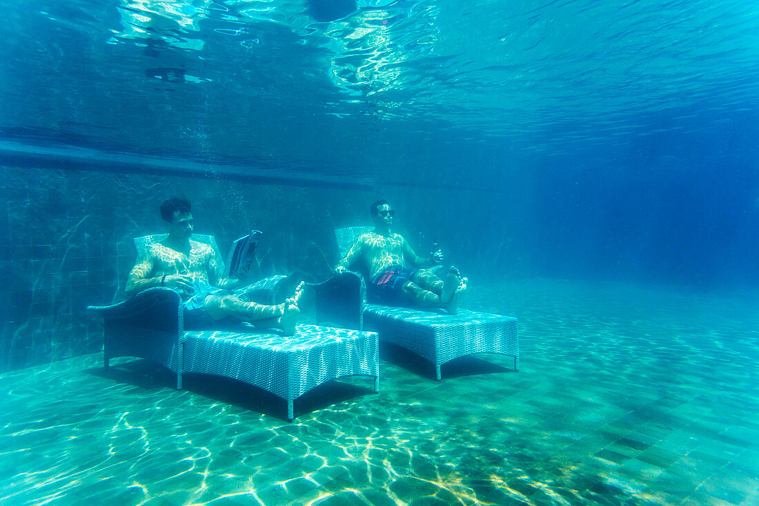 Two Men Lying On Bed Underwater In Pool