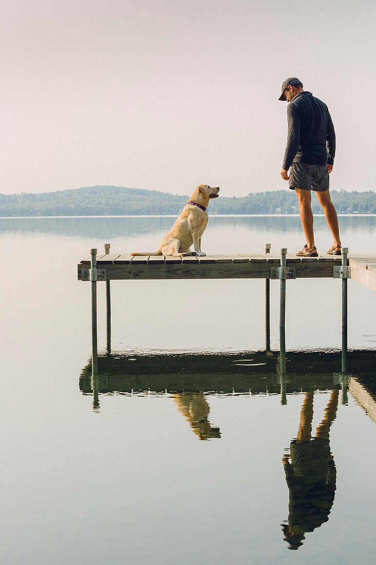 Man With His Dog On The Edge Of A Dock On Caspian Lake