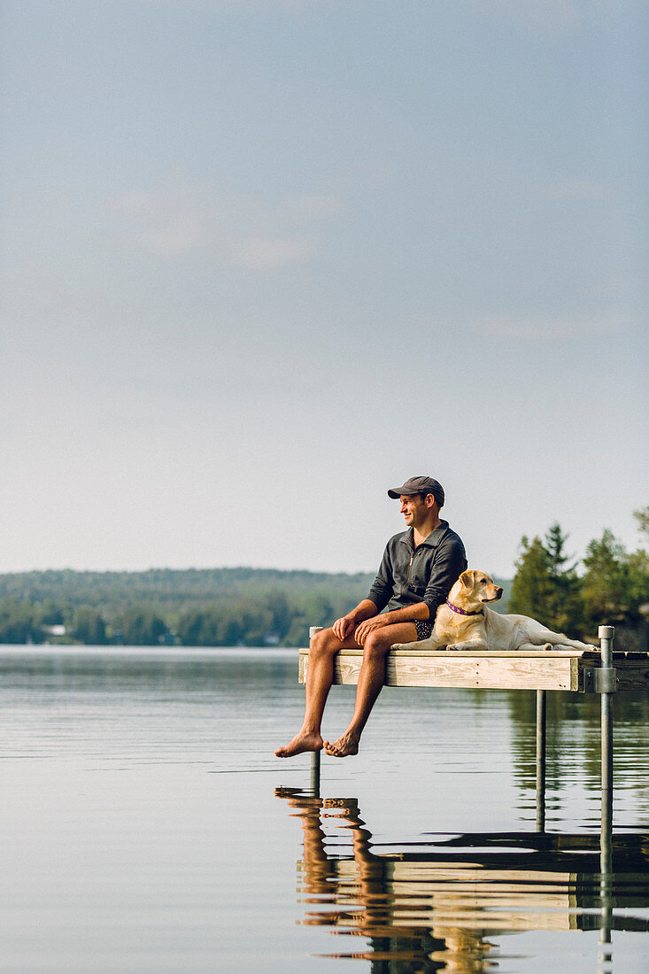 Man Enjoying View With His Dog On The Edge Of A Dock On Caspian Lake