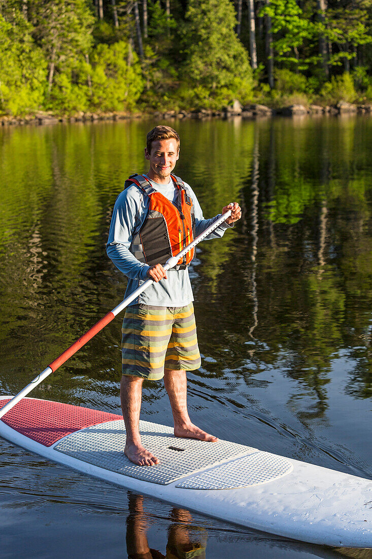 A Man Paddleboarding On Long Pond Near Greenville, Maine