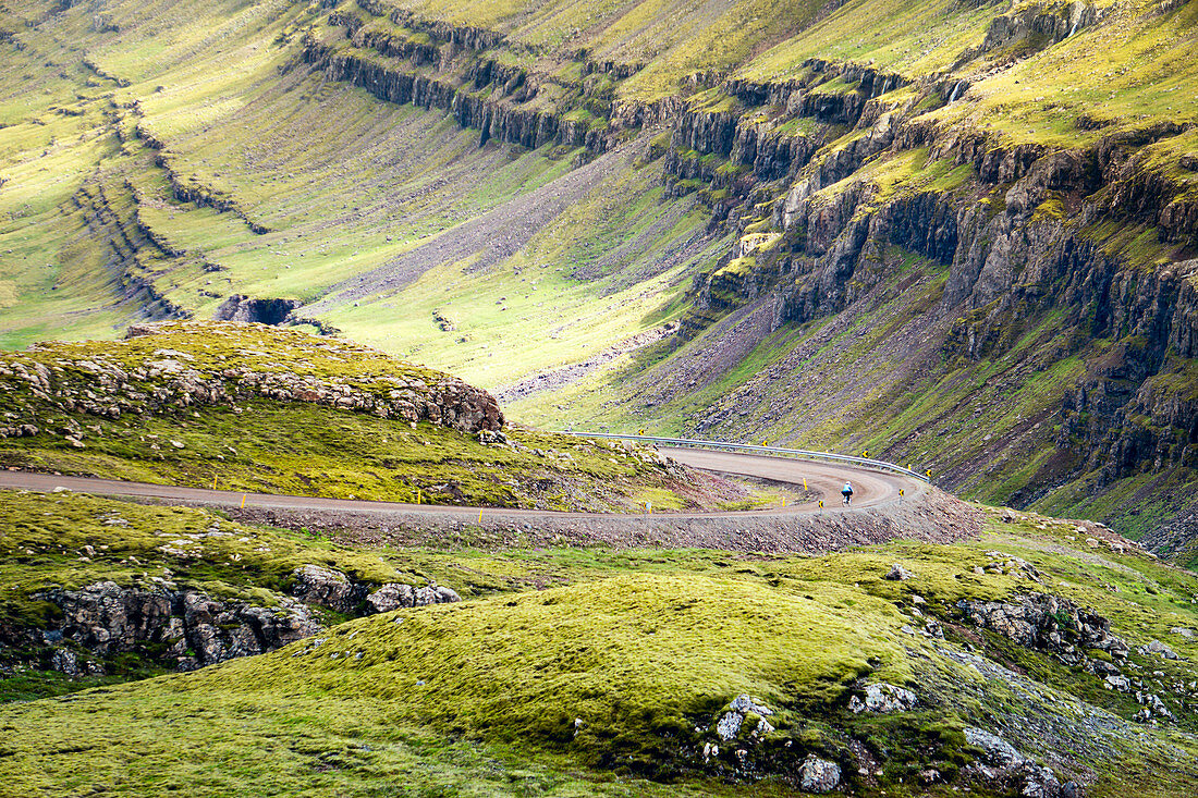 Distant View Of A Woman Rides Along A Mountain Road In North Iceland
